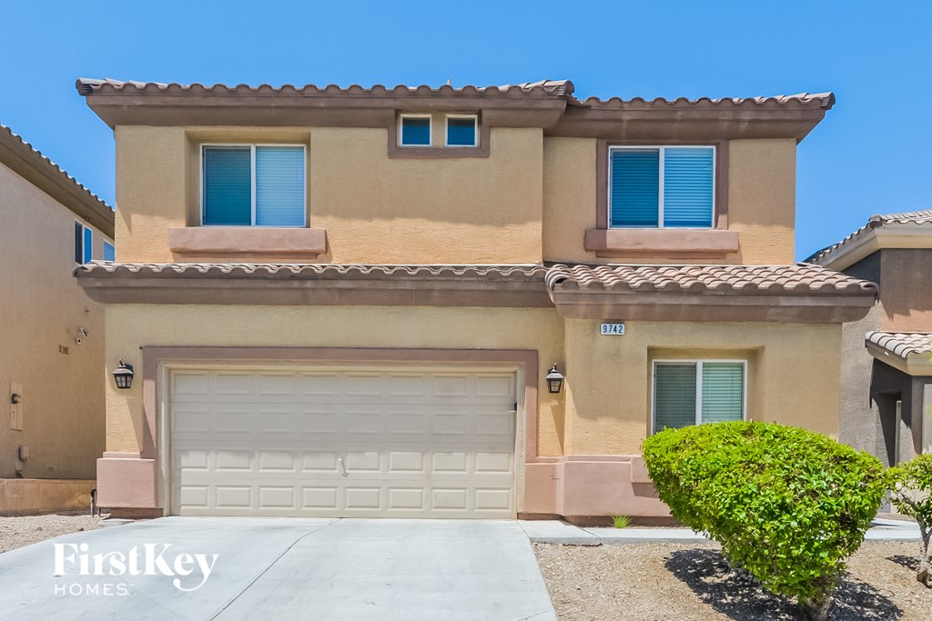 A house with a garage and a driveway in front of it.
