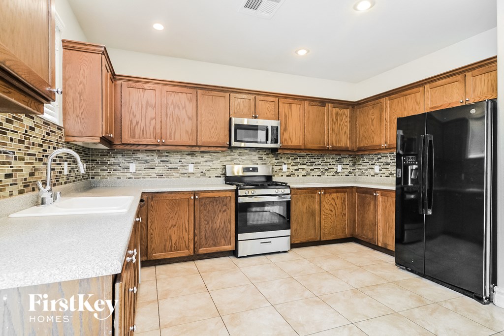 A kitchen with wooden cabinets and a black refrigerator.