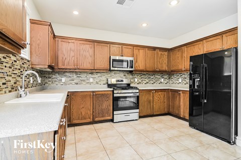 A kitchen with wooden cabinets and a black refrigerator.
