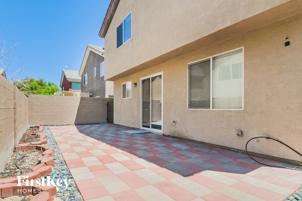 A tan house with a red and white checkered walkway in front.