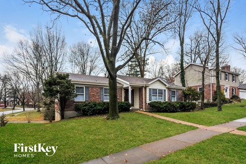 front view of a brick house with trees and grass