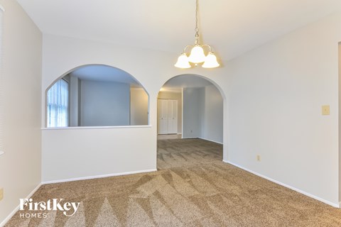 a living room with an arched opening to a dining room
