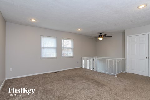 A spacious room with a fan and a white door.