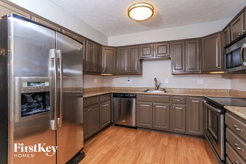 A kitchen with wooden cabinets and a stainless steel refrigerator.