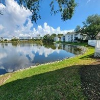 A serene lake surrounded by houses and trees under a partly cloudy sky.