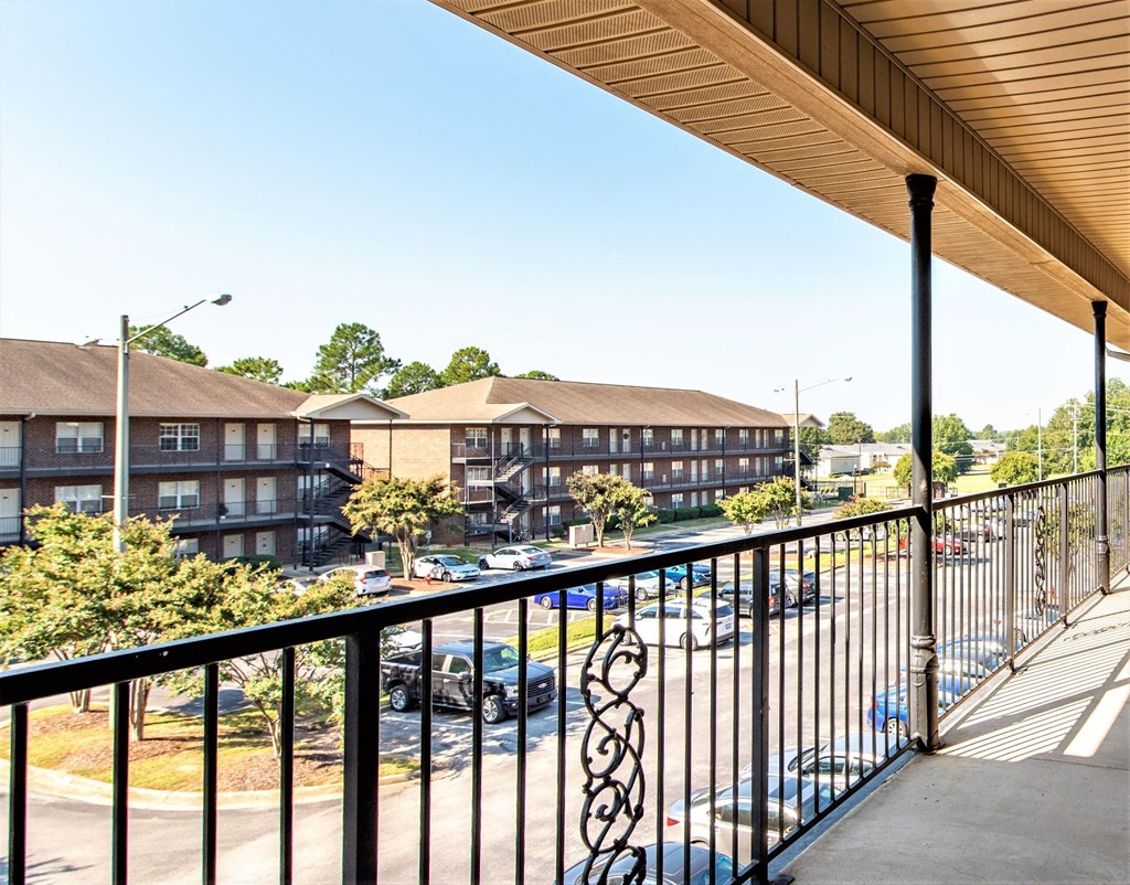 a balcony with a view of a building and a parking lot