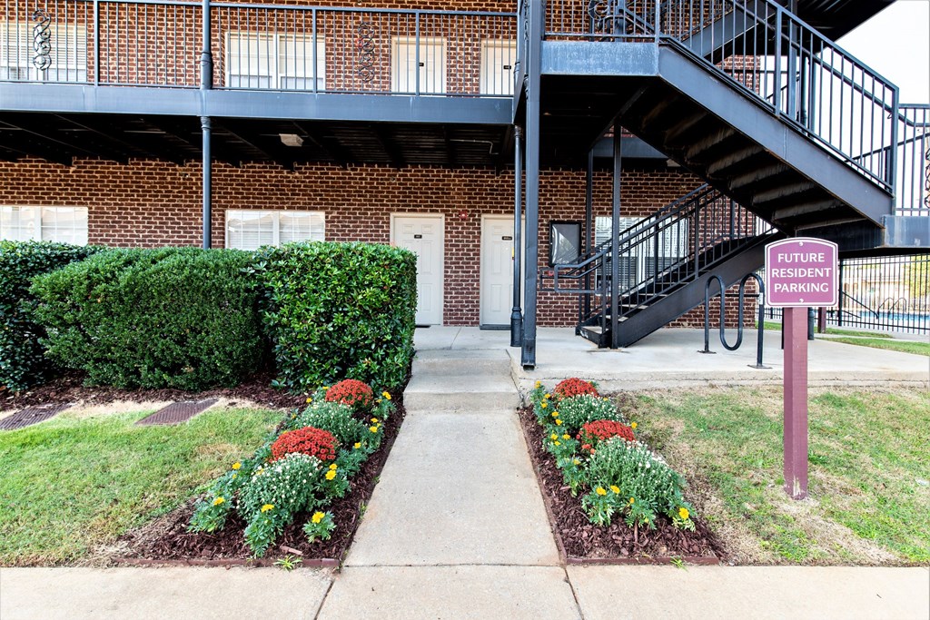 a brick building with a sign in front of a garden