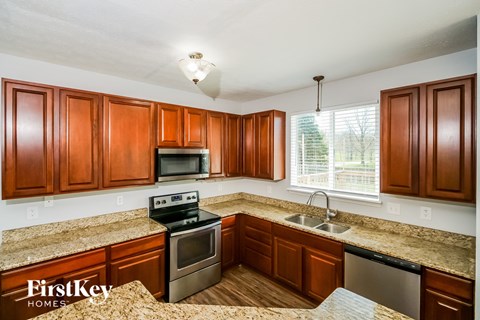 A kitchen with brown cabinets and granite countertops.