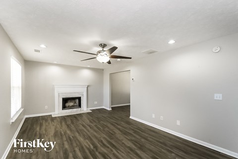 A spacious room with a fireplace and a ceiling fan.
