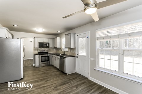 A kitchen with a refrigerator, microwave, oven, sink, and a ceiling fan.