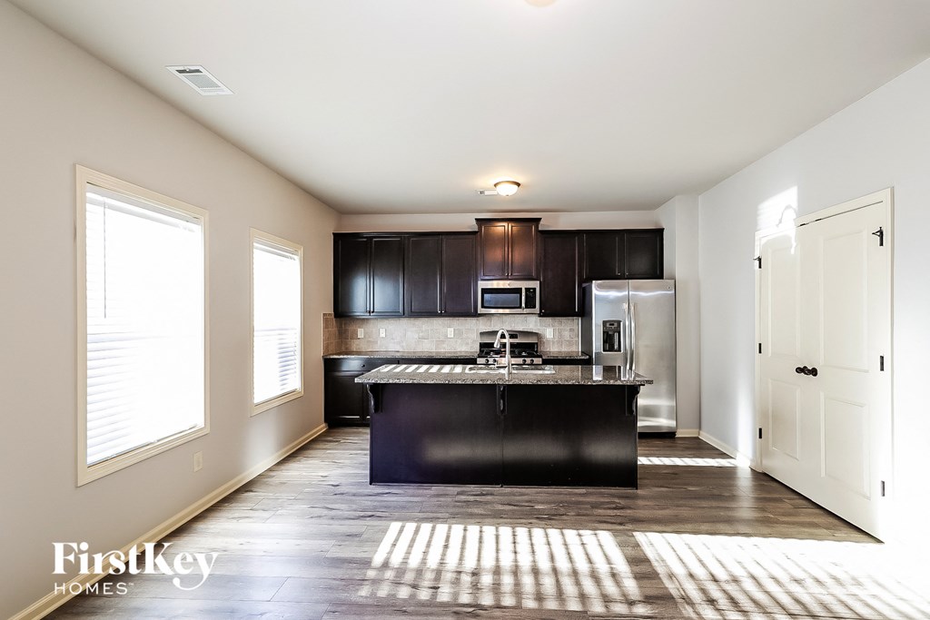 an empty kitchen with black countertops and stainless steel appliances
