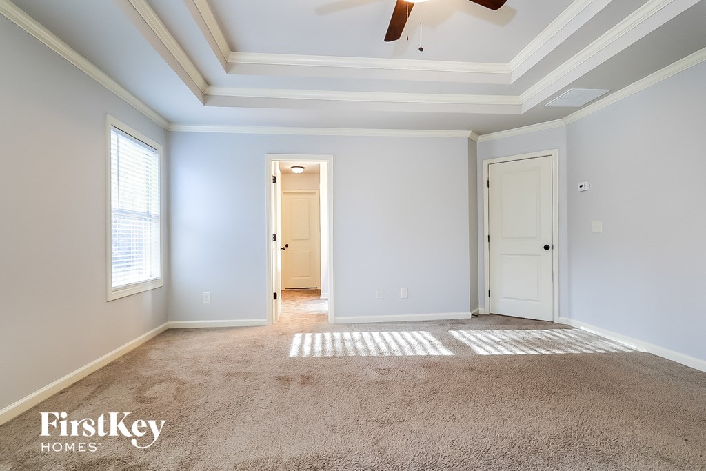 an empty room with a ceiling fan and a door to a hallway