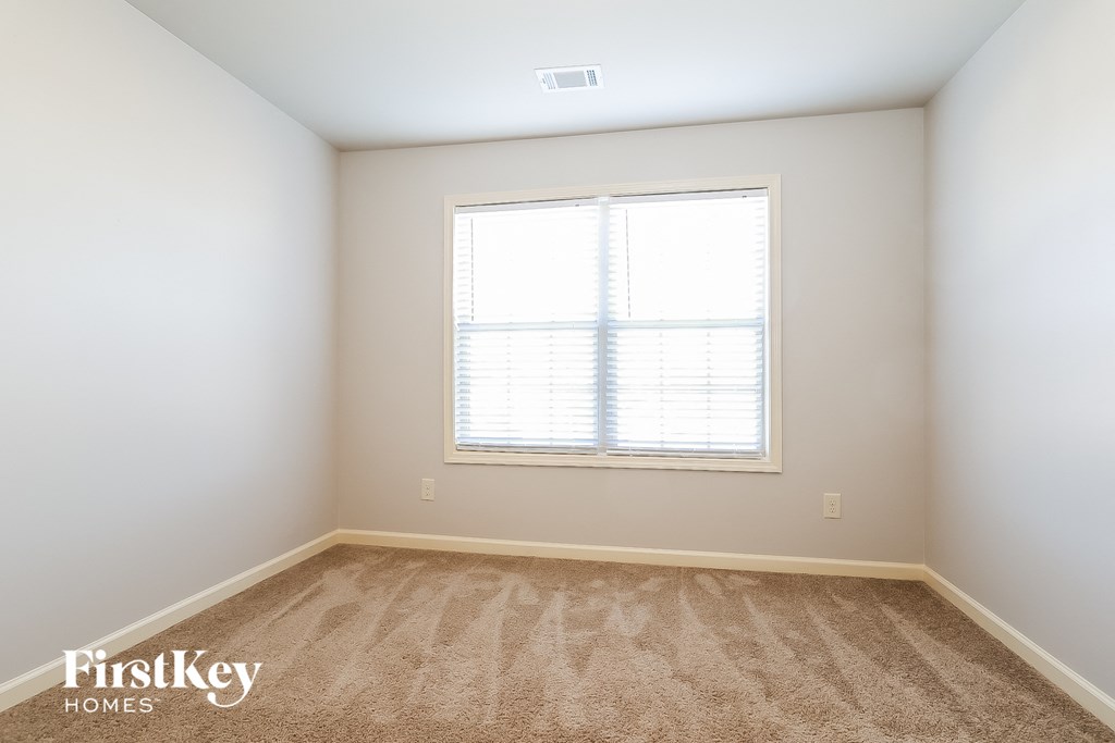 a bedroom with a window and a carpeted floor
