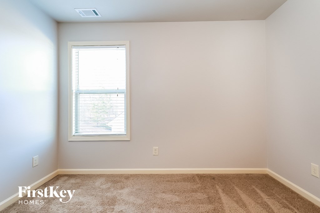 a bedroom with a window and a carpeted floor
