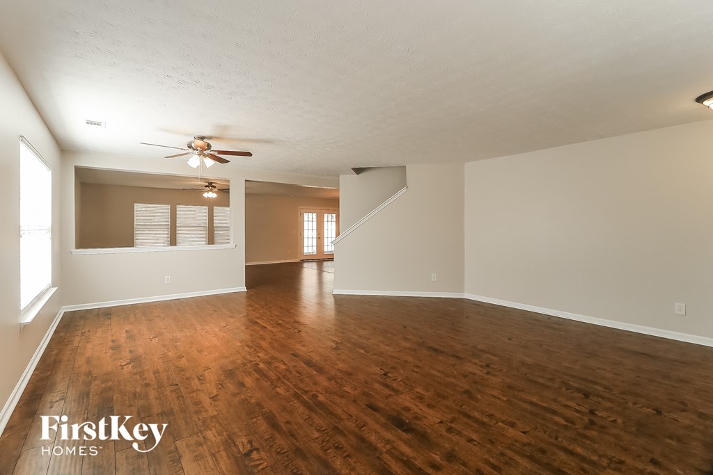 an empty living room with wood floors and a ceiling fan