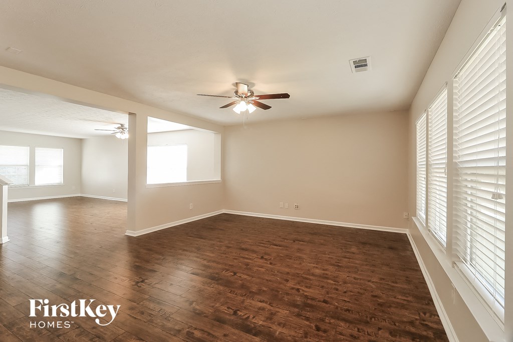 an empty living room with wood flooring and a ceiling fan
