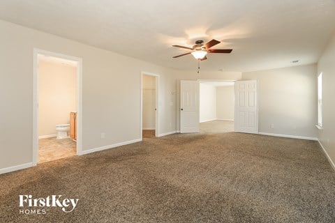 a spacious living room with carpet and a ceiling fan