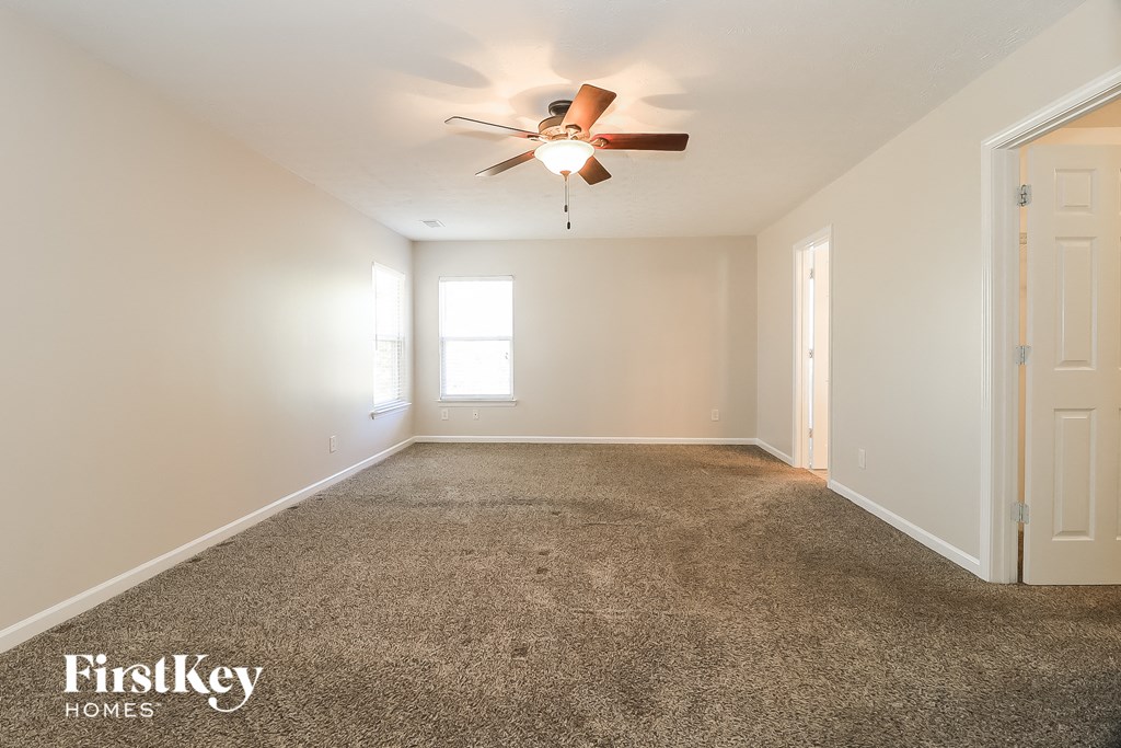 the spacious living room with ceiling fan and carpeting