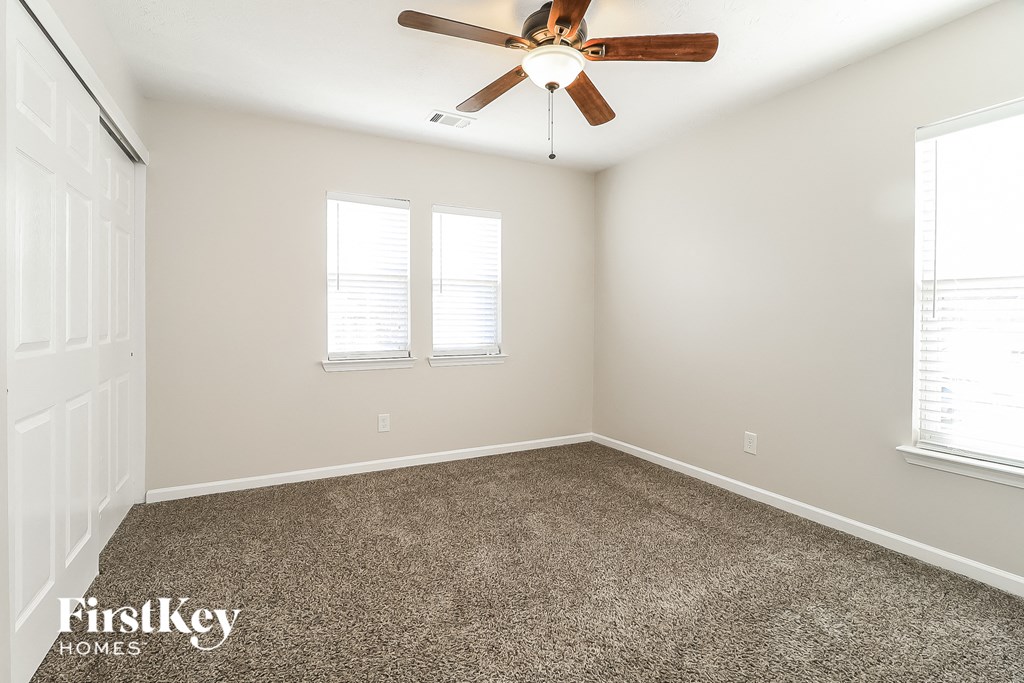 an empty room with a ceiling fan and two windows