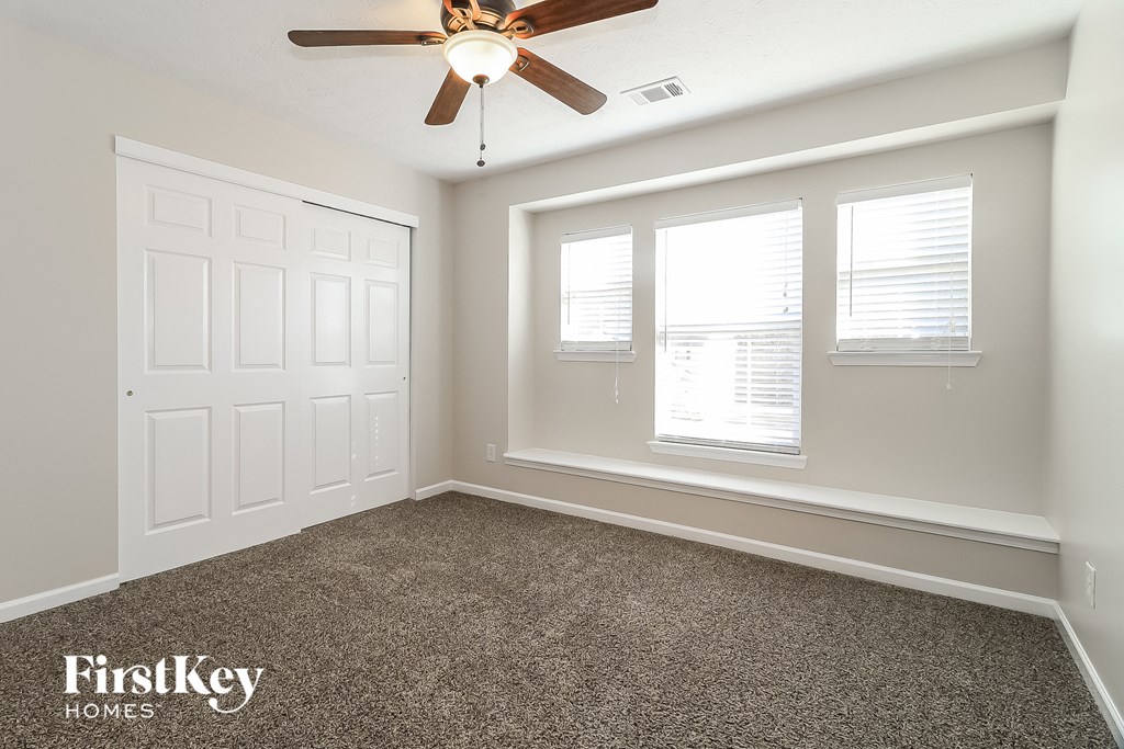 the master bedroom has a large window and a ceiling fan