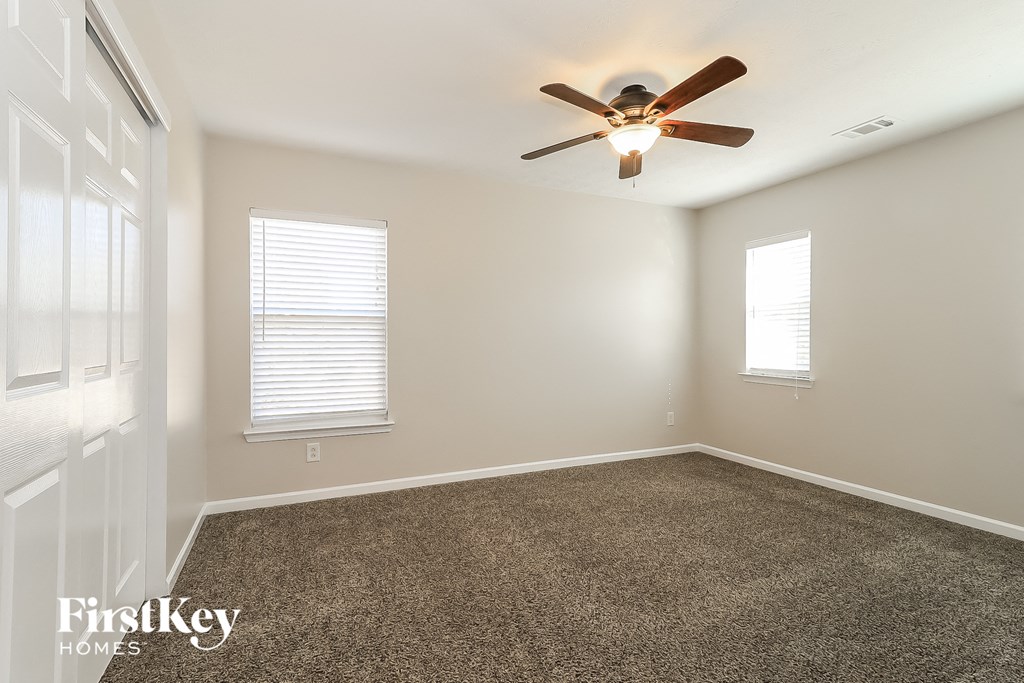 a empty room with a ceiling fan and a carpet