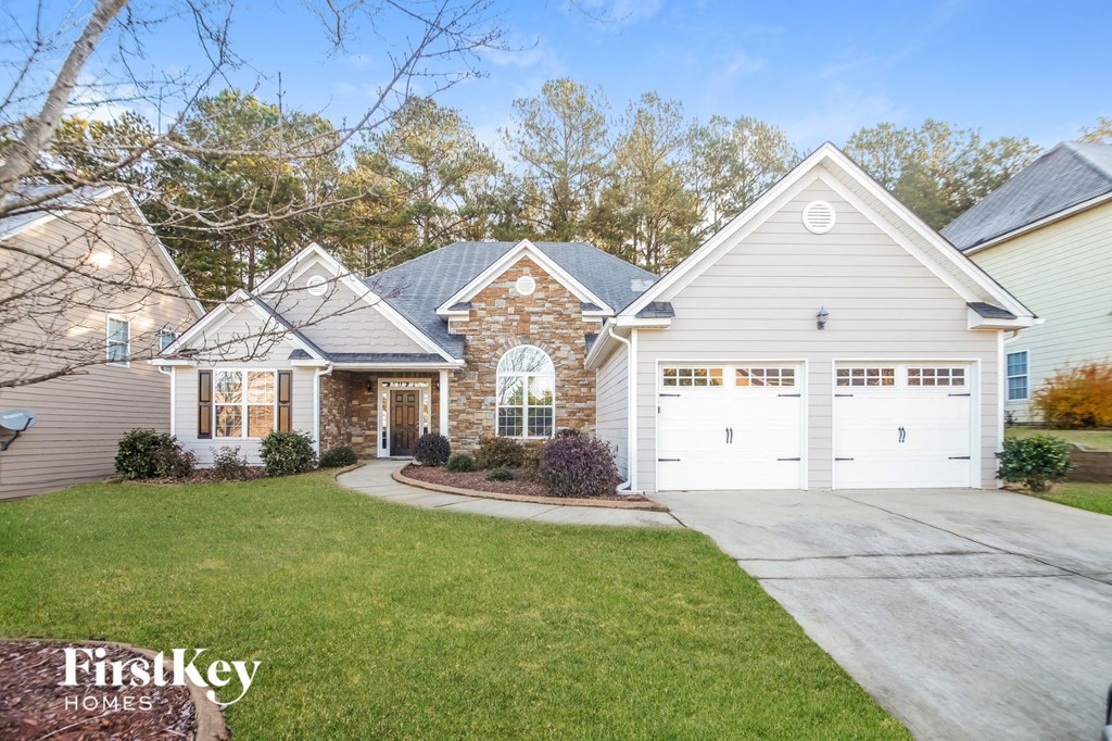 A house with a garage and a driveway in front of it.