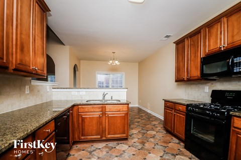 A kitchen with wooden cabinets and a black stove top oven.