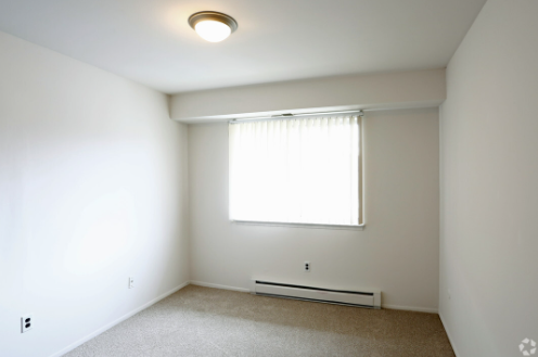 an empty room with a window and white walls