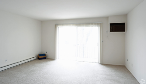 an empty living room with white walls and a sliding glass door