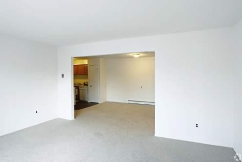 an empty living room with white walls and carpet