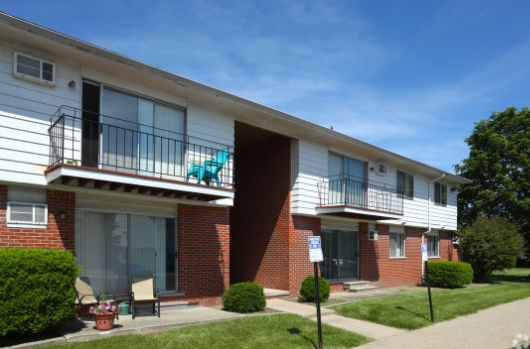 an apartment building with two balconies and a porch with a rocking chair