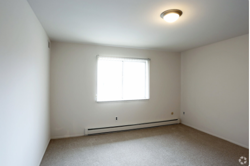 an empty room with a window and white walls