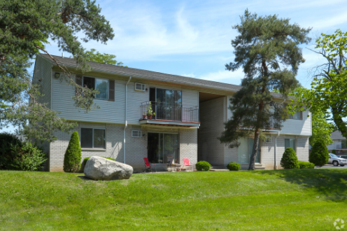 a white house with a yard and a rock in front of it