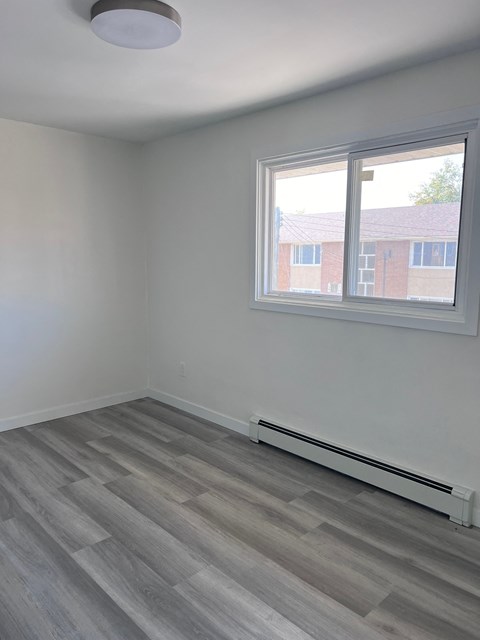 an empty room with wooden floors and a window
