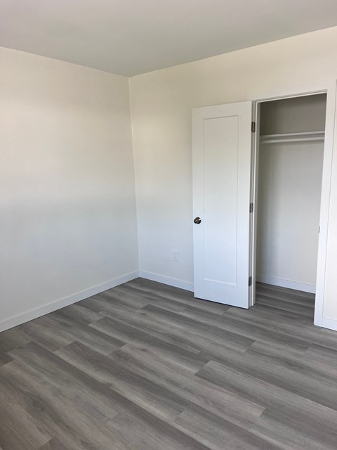 an empty room with wood floors and a closet