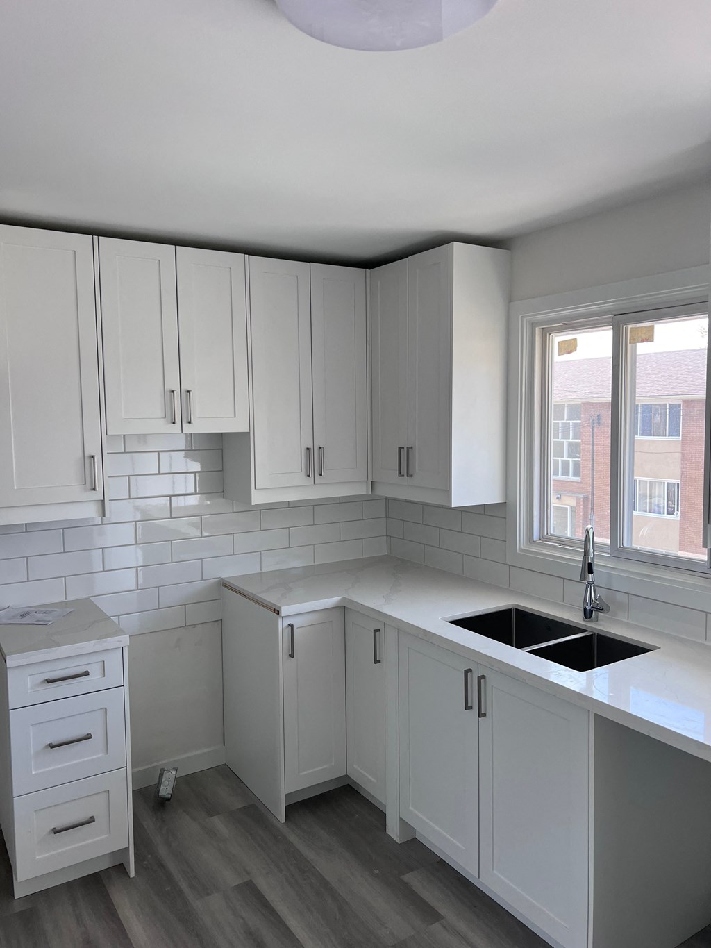 a white kitchen with white cabinets and a black sink