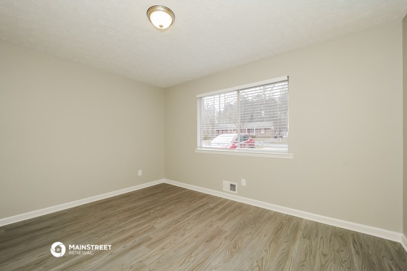 the spacious living room with wood flooring and a large window