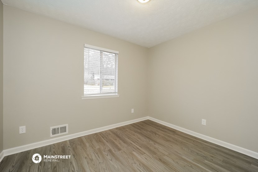 the spacious living room with wood flooring and a window
