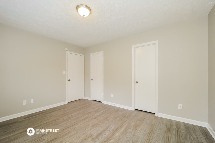 the spacious living room with wood flooring and white walls