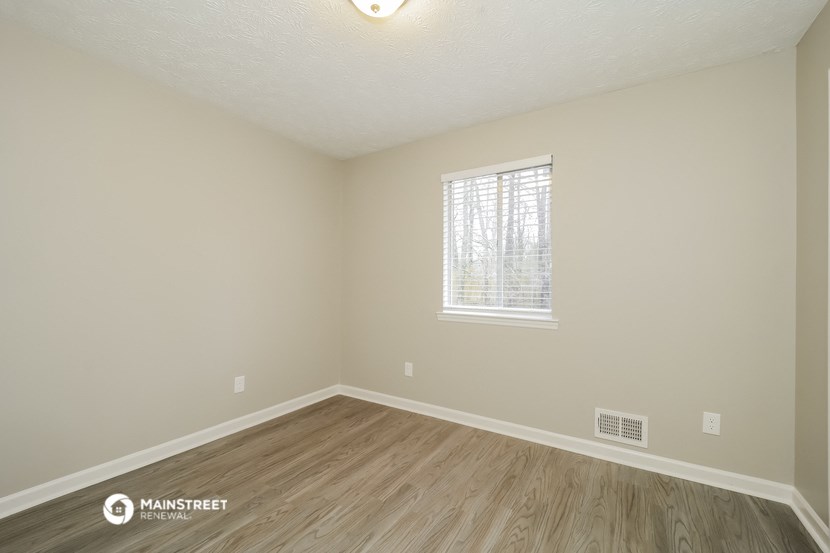 the spacious living room with hardwood flooring and a window
