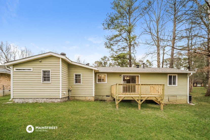 a yellow house with a porch and a wooden deck