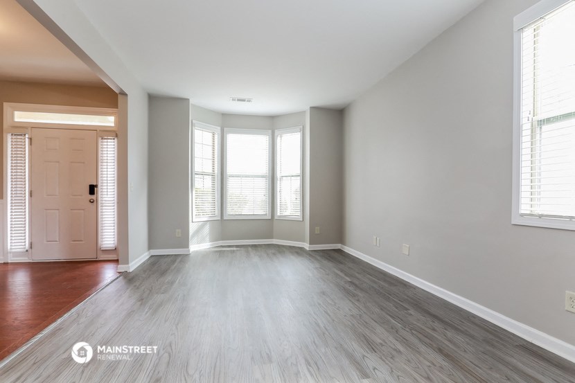 the living room of an empty house with wood flooring and windows
