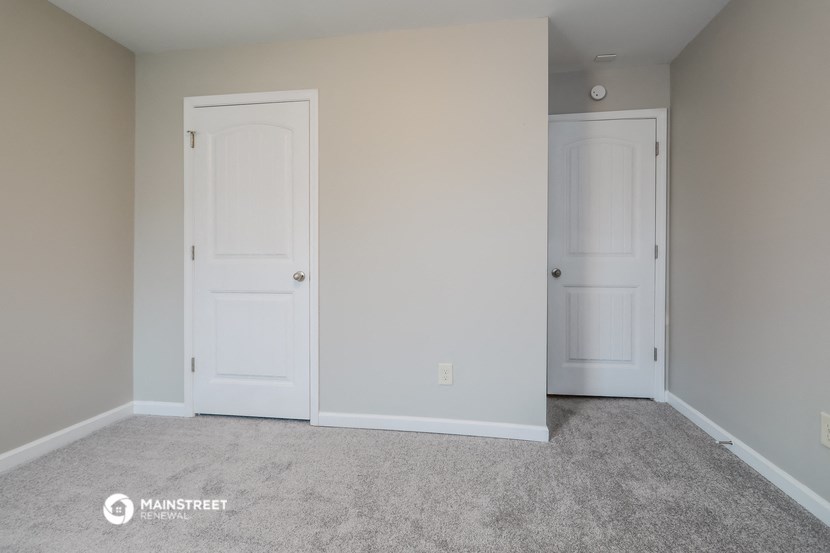 a bedroom with two white doors and a carpeted floor