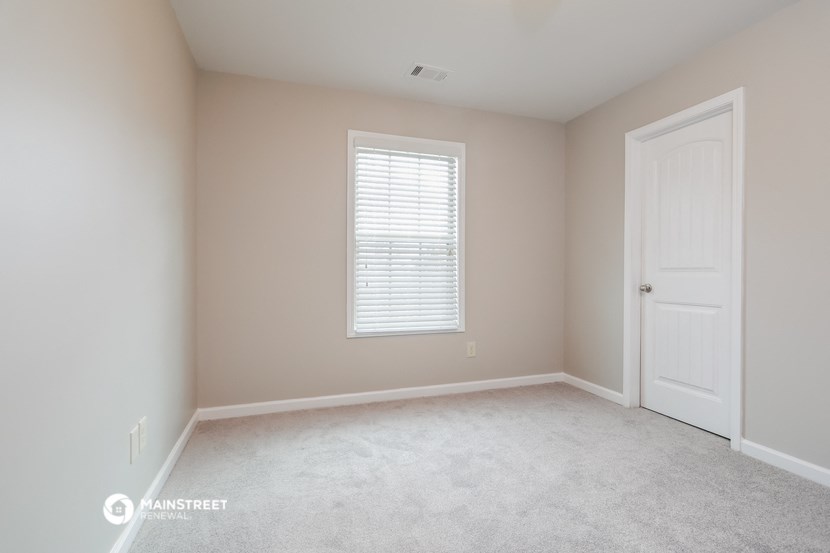 an empty room with a white door and a window