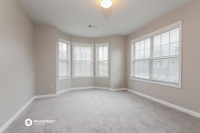 an empty room with three windows and a carpeted floor