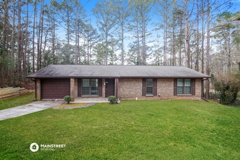 a small brick house in the middle of a grassy yard