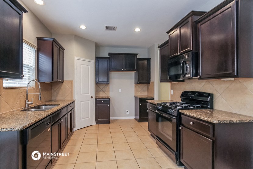 a kitchen with black cabinets and a sink and a stove