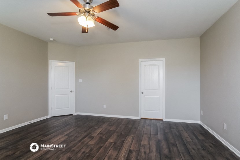 the spacious living room with hardwood floors and a ceiling fan