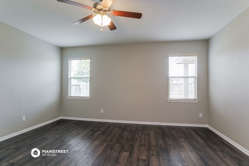 the spacious living room with hardwood floors and a ceiling fan