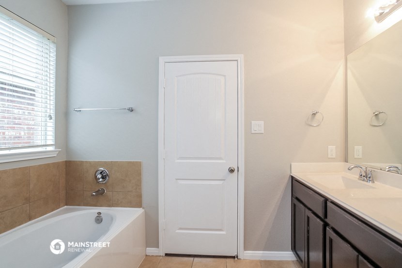 a bathroom with a tub and a sink and a white door